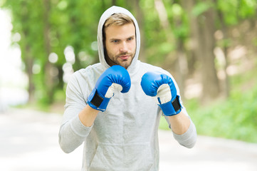 Training for big day. Man athlete on concentrated face with sport gloves practicing boxing punch,...