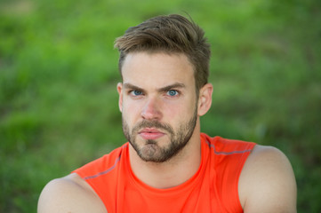 Taking minute break. Runner relaxing in shadow. Man with bristle strict face, grass background. Man...