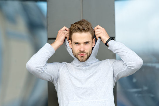 Feeling casual. Guy bearded attractive casual hooded. Man with bristle serious face, urban background, defocused. Man unshaven guy looks handsome casual hooded. Masculinity concept
