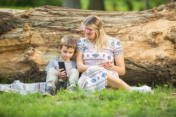 Mother and son in park using cellphones