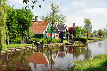 Fototapeta na wymiar Landscape of the village in the Netherlands. The wooden houses are colourful and set along a picturesque lake surrounded by trees .