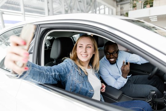 African man with a European girl taking pictures on the phone in the car