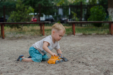 Cute little boy plays with a toy on the playground