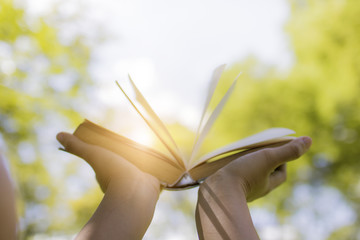 hand holding book on sky, knowledge and wisdom concept