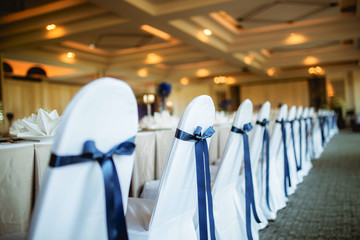 Chairs with ribbon decor are arranged in restaurant.