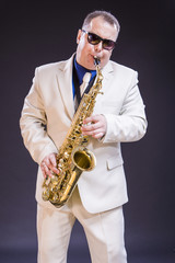 Music Themes and Ideas. Tranquil Caucasian Mature Saxophonist Against Black Background.