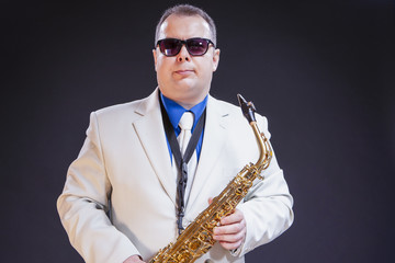 Music Themes. Portrait Of Confident Mature Male Saxophonist Posing with Instrument in White Suit...