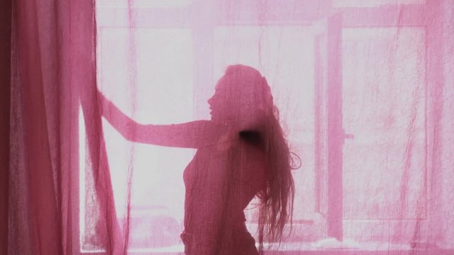 Sexy girl silhouette dancing behinde the tulle sunlight in the background, silhouette concept