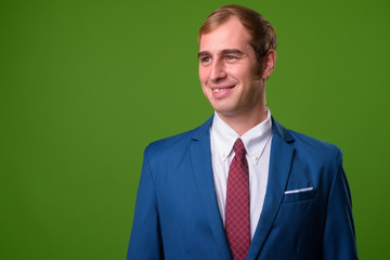 Young businessman against green background