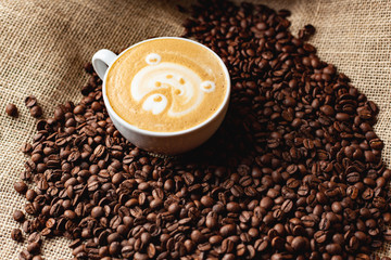 Cappuccino with a pattern on the background of coffee beans
