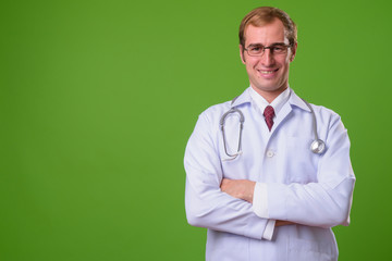 Young man doctor against green background