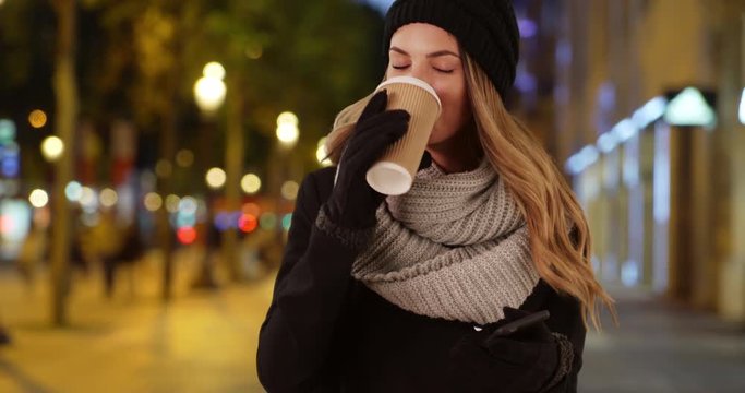 Attractive woman with her coffee laughing at boyfriend's text, Smiling woman checks her phone messages outside at night, 4k
