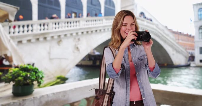 Travel photographer in Venice taking picture with camera, Happy woman tourist by the Rialto Bridge photographing vacation, 4k