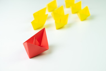 Big red paper ship origami lead in front of others followers small yellow fleet, leadership, influencer, KOL, key opinion leader concept