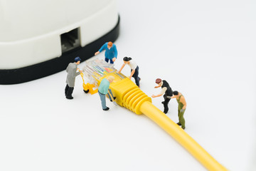 Internet network, telecommunication connecting people concept, group of miniature people figures help moving LAN, Local Area Network yellow cable line to connect with router device