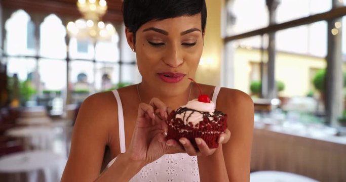 Black woman indulging in fancy red velvet cupcake, Portrait of woman taking messy bite of dessert, 4k