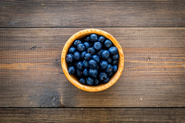 Fresh recently picked blueberries in bowl on dark wooden background top view copy space closeup
