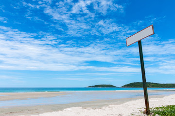 Signs by the sea, golden sand beach, Beautiful white clouds on blue sky over calm sea with sunlight reflection and the island is full of trees.