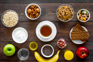 Set of products for healthy vegetarian breakfast. Fruits, oatmeal, yogurt, nuts, crispbreads, chia on dark wooden background top view