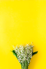 Small and fragrant spring flowers. Bouqet of lily of the valley flowers on yellow background top view copy space