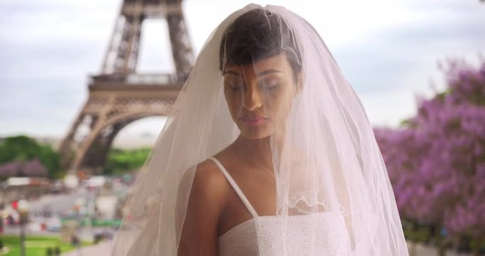 Blushing bride in Paris, France poses for portrait, Black woman in cute elegant wedding dress and veil, view of Eiffel Tower in background, 4k