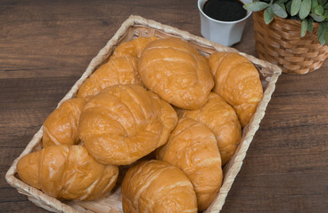 Freshly baked homemade croissants and black coffee on wooden cutting board, top view