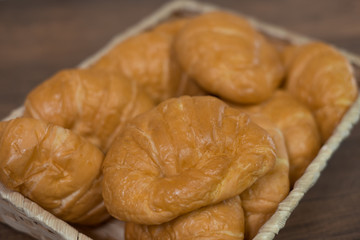 Freshly baked homemade croissants and black coffee on wooden cutting board, top view