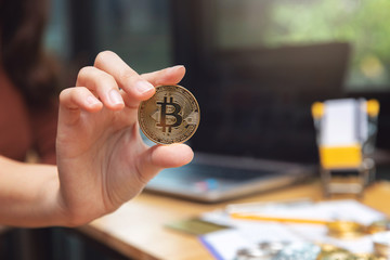 Woman holding cryptocurrency golden bitcoin coin.