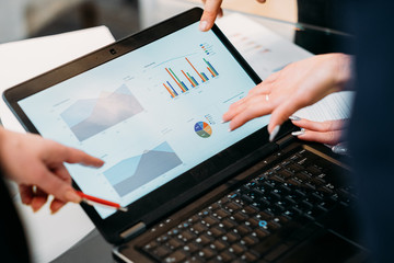 business meeting. problem solving, issue management. troubleshooting. communication, information exchange. executives discussing company results reading papers with graphical data on laptop