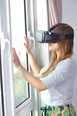 Young woman wearing virtual reality glasses at home.