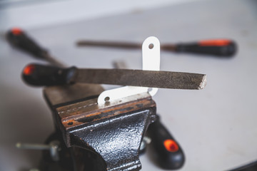 Metal corner clamped in bench screw. Above is file