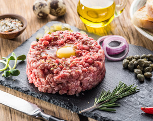 Steak tartare served with raw quail egg yolk and other tartare ingredient. Meat dish.
