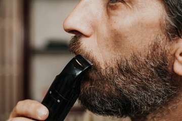 Cutting  mustache with black trimmer close-up