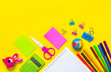 Stationary, back to school,summer time, creativity and education concept.School supplies scissors, pencils, paper clips,note,stapler and notepad, globe on yellow background,flatlay.Mock up.Top view.