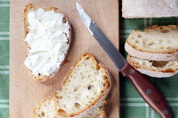 piece of bread smeared with soft cheese on a wooden board