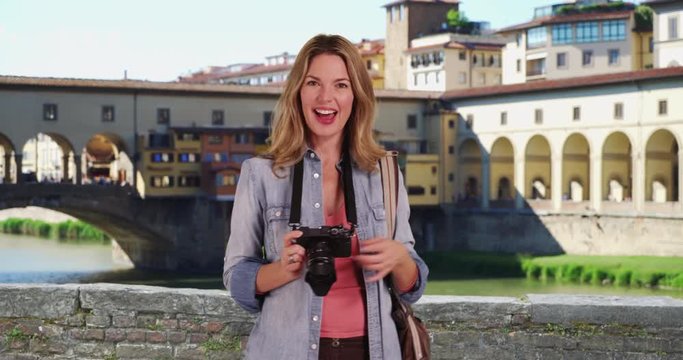 Travel photographer taking pictures of the Ponte Vecchio Bridge, Portrait of woman tourist in Florence talking directly to camera, 4k