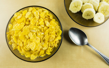 Nutritious quick breakfast for children and adults. Bowl with cornflakes with cold milk and banana on a separate plate.