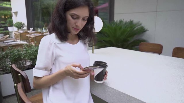 Super slow motion, young business lady with smartphone in city cafe