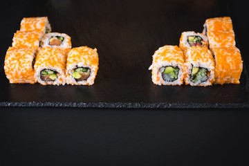 A set of different sushi rolls with caviar on black background
