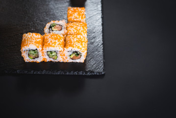 A set of different sushi rolls with caviar on black background