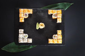 Obraz premium A set of different sushi rolls with caviar on black background