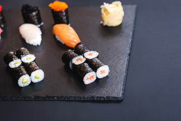 A set of different sushi rolls with caviar on black background