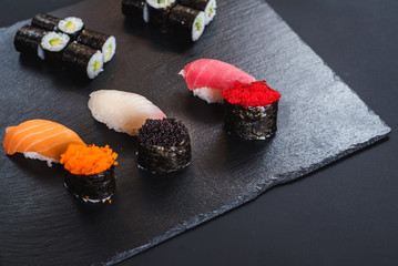 A set of different sushi rolls with caviar on black background