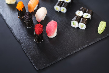 A set of different sushi rolls with caviar on black background