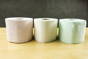 Three rolls of toilet paper in various colors (white, red, green).