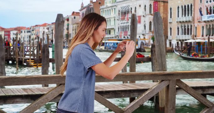 Woman tourist taking pictures of summer vacation in Venice, Pretty Caucasian woman takes picture of gondola boat to share with family and friends, 4k