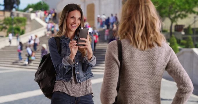 Young white female using camera phone to take a photo of her friend in Rome, Italy, Gorgeous brunette takes photo of blonde friend while traveling in Rome, Italy, 4k