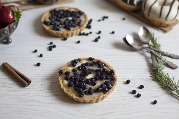 Obraz na płótnie Canvas Closeup of blueberry tart on white wooden table; selective focus background.