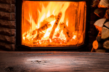 Wooden table top and burning warm fire at the background.