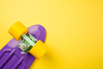 purple youth skateboard on yellow background. children's plastic mini cruiser board. minimalism, flat lay, copy space